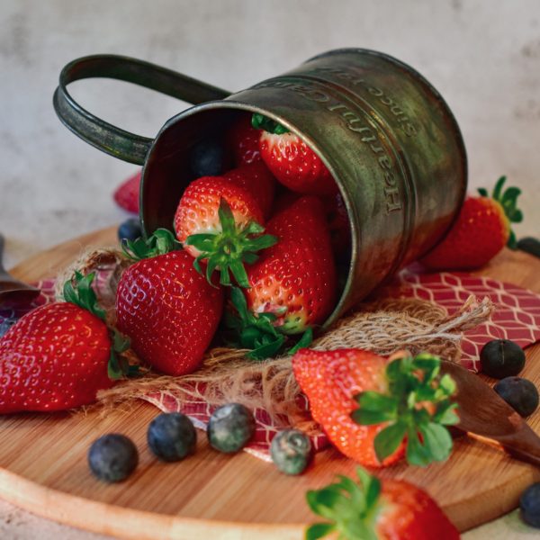 strawberries and blueberries spilling out of mug